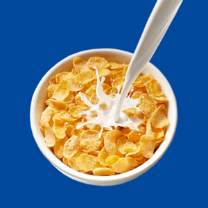 Schüssel mit Cornflakes, in die geraden Milch gegossen wird